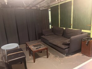Ein Wohnzimmer mit einer Couch, einem kleinen Tisch, einem Sessel und einem Korbwannenmöbel.