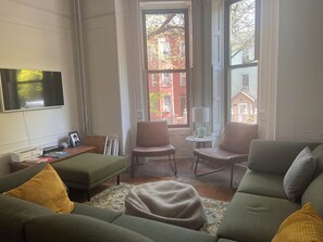 Relax in this stylish living room with a large flat-screen TV, comfortable sofa, and armchairs.