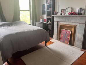 Cozy retreat with a large bed, classic fireplace, and bookshelf.