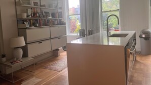 Eine moderne Küche mit einer großen Kochinsel, eingebauten Regalen und Blick ins Freie.