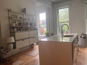 Enjoy meals in the kitchen with a central island and oven, adjacent to a dining area with a table and chairs.