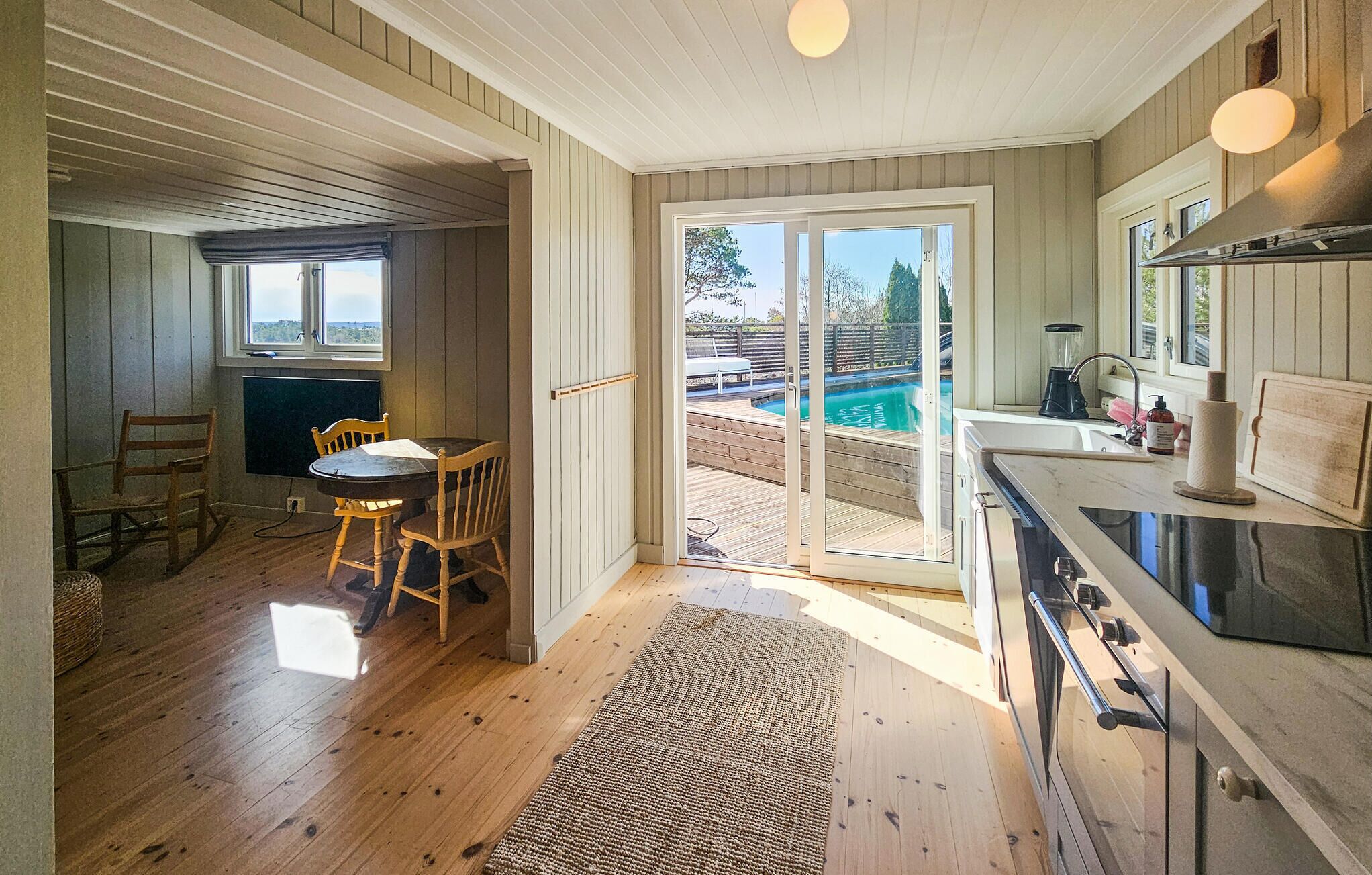 A kitchen with a large island, a dining area with a table and chairs, and a sliding glass door leading to a pool area.