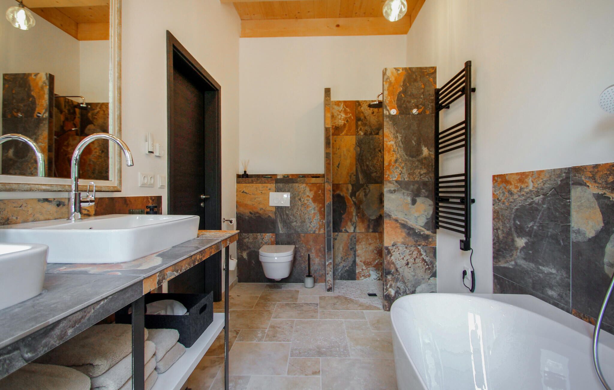 Une salle de bain avec une grande baignoire, deux lavabos, des toilettes et un porte-serviettes.