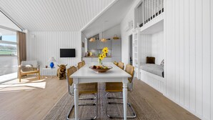 A modern dining area with a white table, chairs, and a large window. - Lovely home in Stege with sauna (Stege)