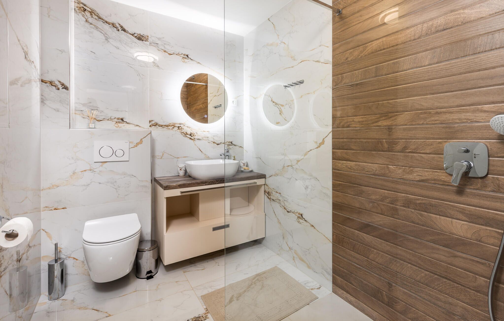 A modern bathroom with a marble vanity, a wooden shower wall, and a toilet.