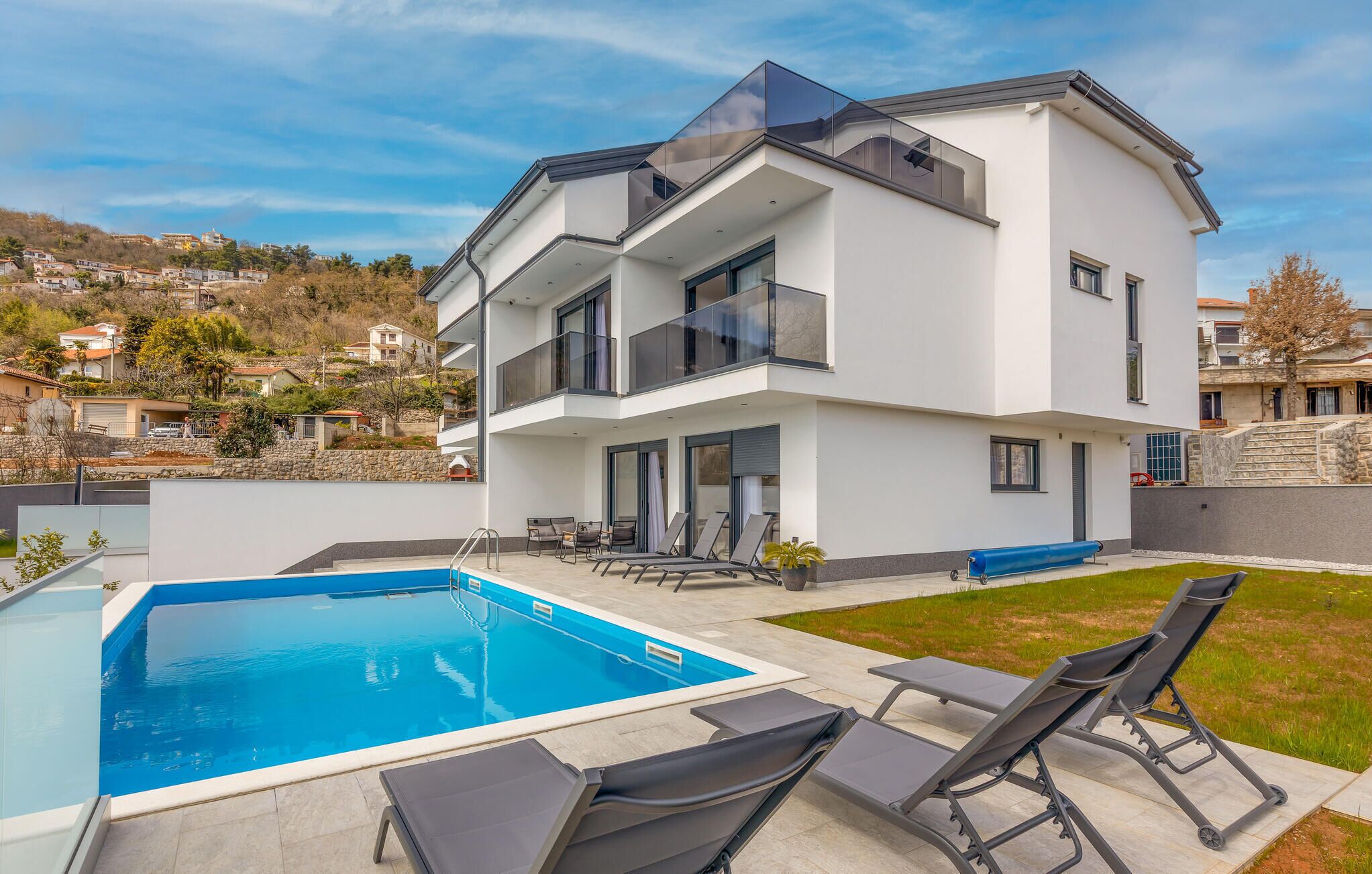 Ein modernes, zweistöckiges Haus mit Pool und Außenbereich.