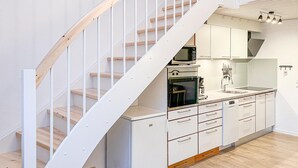 Een moderne keuken met witte kasten, een inbouwoven en een magnetron.