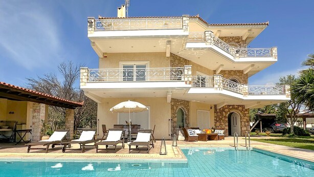 Un bâtiment à deux étages doté d’une piscine, d’un espace extérieur aménagé et d’une façade en pierre.