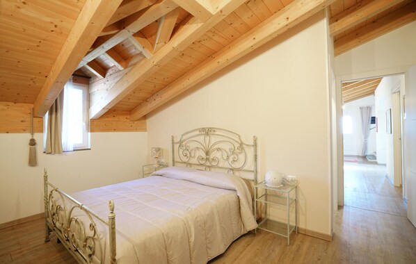 A bedroom with a wooden ceiling, a metal bed frame, a bedside table with a lamp, and a window. - Lovely home in Imperia with WiFi (Imperia)
