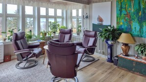 A room with four leather chairs, large windows, a painting, and several potted plants. - Awesome home in Bekkjarvik (Bekkjarvik)