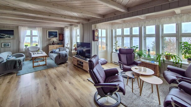 A spacious living room with wooden floors, a large window with a view, a television, and several seating options. - Awesome home in Bekkjarvik (Bekkjarvik)