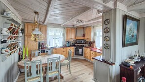 A kitchen with wooden cabinets, a dining table with chairs, a chandelier, and a painting on the wall. - Awesome home in Bekkjarvik (Bekkjarvik)