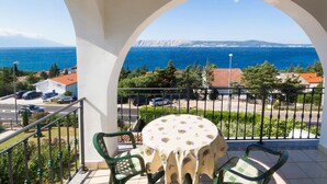 A balcony with a table and chairs, overlooking a coastal view with houses and parked cars. - Awesome apartment in Novi Vinodolski with WiFi (Novi Vinodolski)