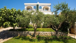 A building with a white facade, multiple balconies, and a stone wall in the foreground. - Awesome apartment in Novi Vinodolski with WiFi (Novi Vinodolski)