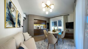Un salon moderne comprenant un canapé, une table à manger avec des chaises, un coin cuisine et un téléviseur.