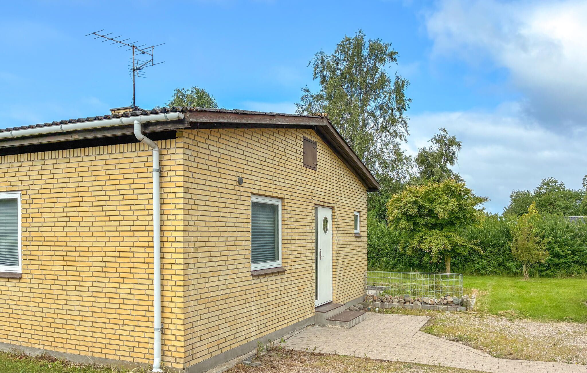 A small brick building with a metal roof, a door, and a window.