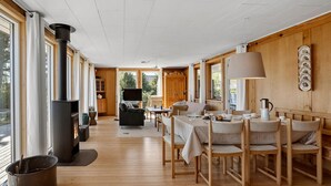 A cozy cabin interior with a fireplace, wooden furniture, and large windows.