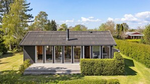 A modern house with a sloped roof, large glass windows, and a wooden deck.