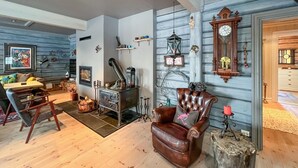 A cozy living room with a fireplace, a leather armchair, and a rustic wooden wall. - Nice home in Sjusjøen with WiFi (Sjusjøen)