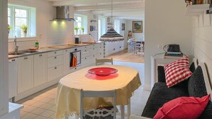 A modern kitchen with white cabinets, a central island, and a dining area with a table and chairs. - 1 bedroom lovely home in Kättilstorp (Kättilstorp)