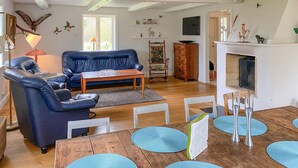 A living room with a blue sofa, a wooden coffee table, and a fireplace. There are decorative items on the mantel and a bookshelf in the background. - 1 bedroom lovely home in Kättilstorp (Kättilstorp)