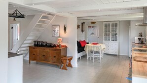 A spacious kitchen with a wooden cabinet, a dining table, and a staircase leading to an upper level. - 1 bedroom lovely home in Kättilstorp (Kättilstorp)