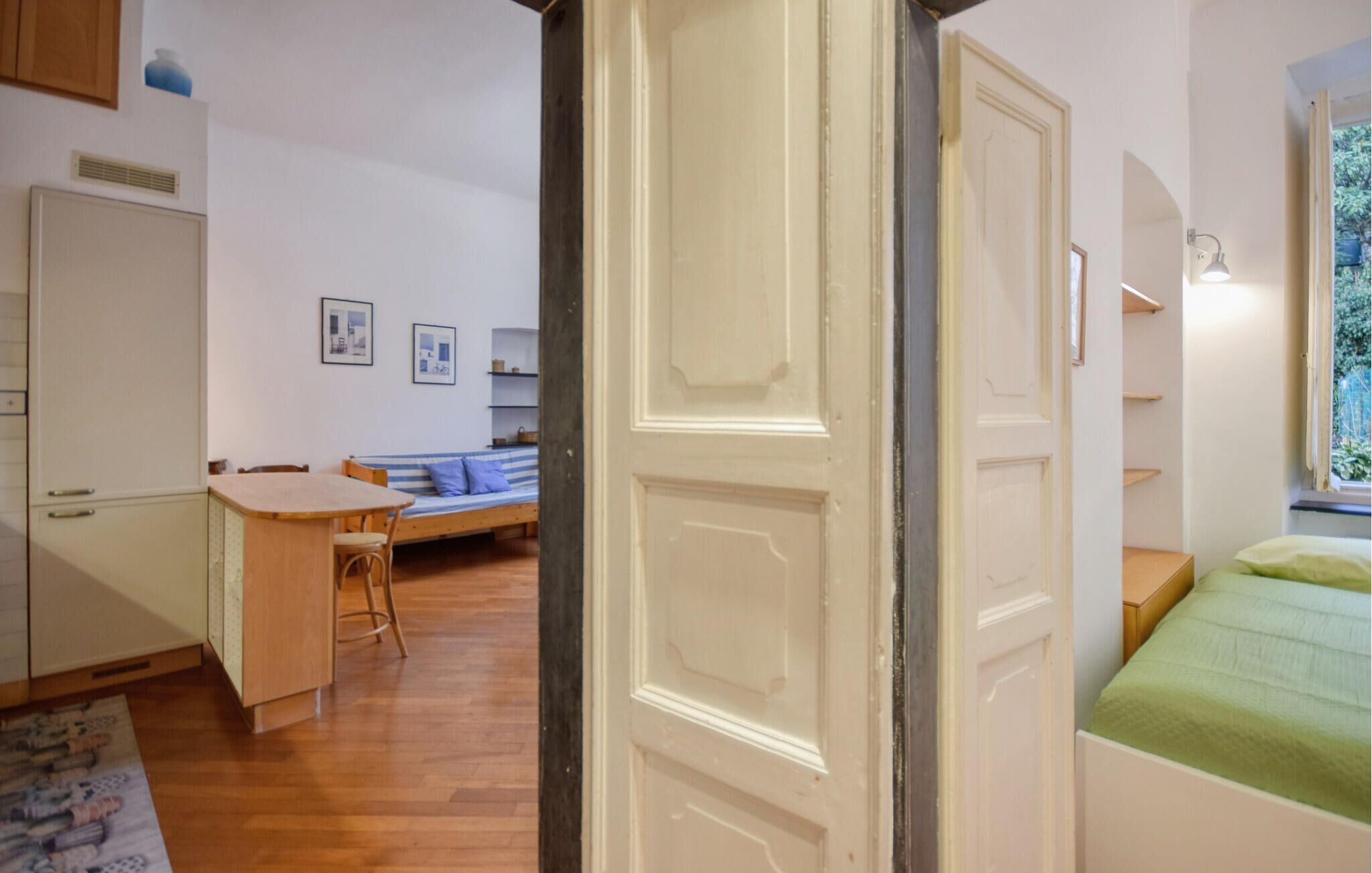 Una stanza accogliente con una scrivania in legno, un divano a righe blu e un letto con copriletto verde.