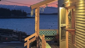 A wooden deck with a bench, a small table, and a sign reading "Village Ice Cream Shop."