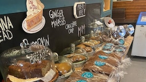 A bakery display with various baked goods, including ginger molasses bread and chocolate chip muffins.
