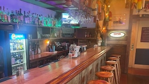 A bar with wooden stools, a Pepsi refrigerator, and a Harpoon sign.