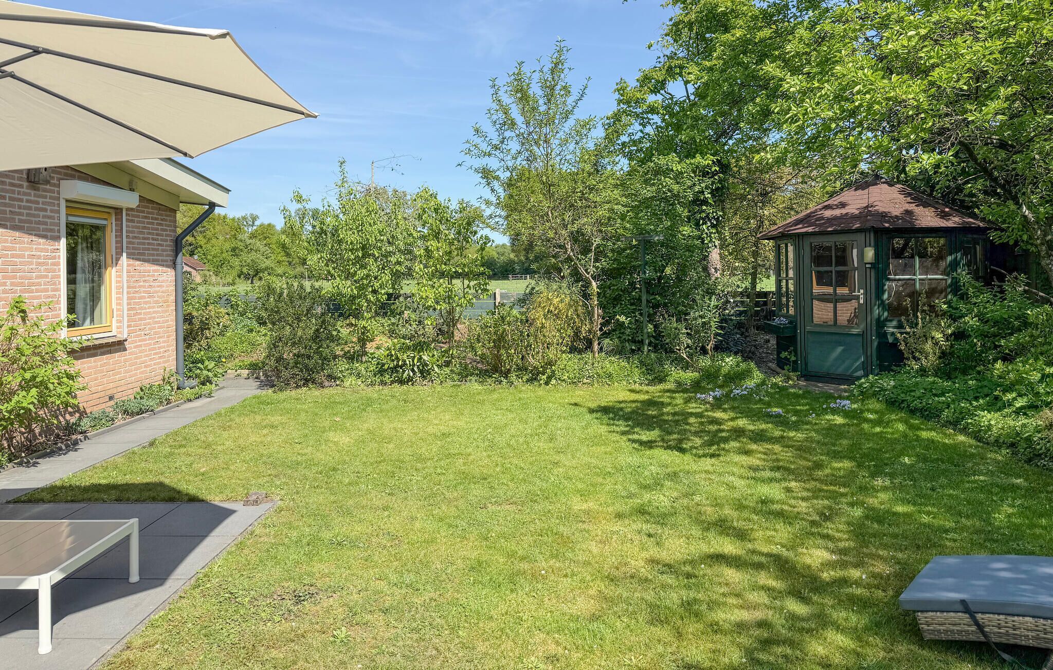 Ein Garten mit einer Terrasse, einem Tisch, Stühlen, einem Pavillon und einem Ziegelhaus.