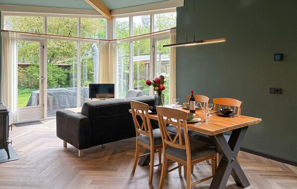 A dining area with a table, chairs, a television, and a view of the outdoors.