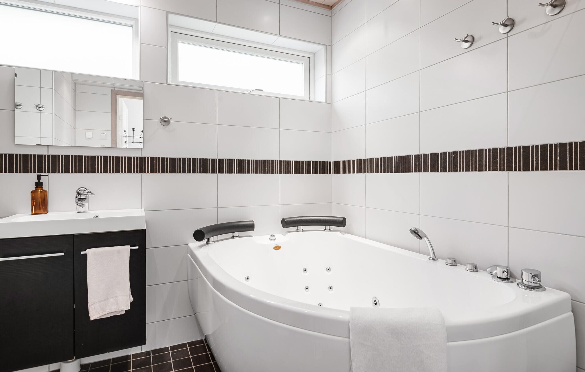 A modern bathroom with a freestanding bathtub, a vanity with a mirror, and a window above the sink.