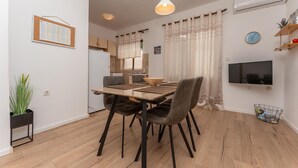 A modern dining area with a wooden table, four chairs, and a television on the wall. - Awesome apartment in Biograd na Moru with WiFi (Biograd na Moru)