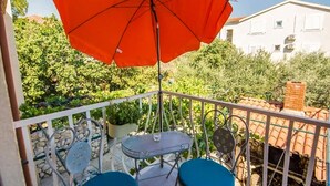 A balcony with a red umbrella, a table, and two chairs. - Awesome apartment in Biograd na Moru with WiFi (Biograd na Moru)