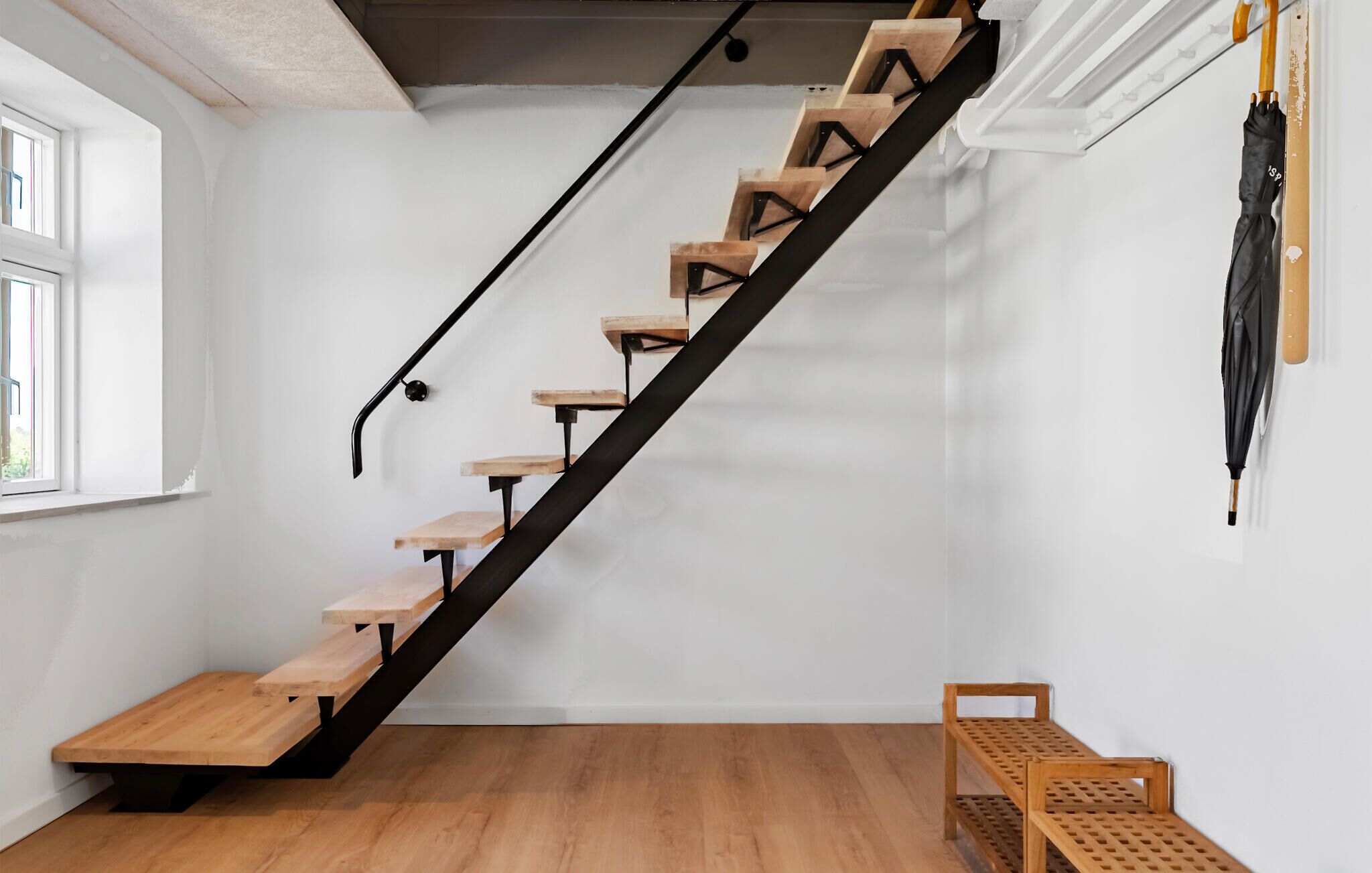 Eine Treppe mit Holzstufen und schwarzen Metallgeländern, die zu einer Aussichtsplattform mit einer hölzernen Bank führt.