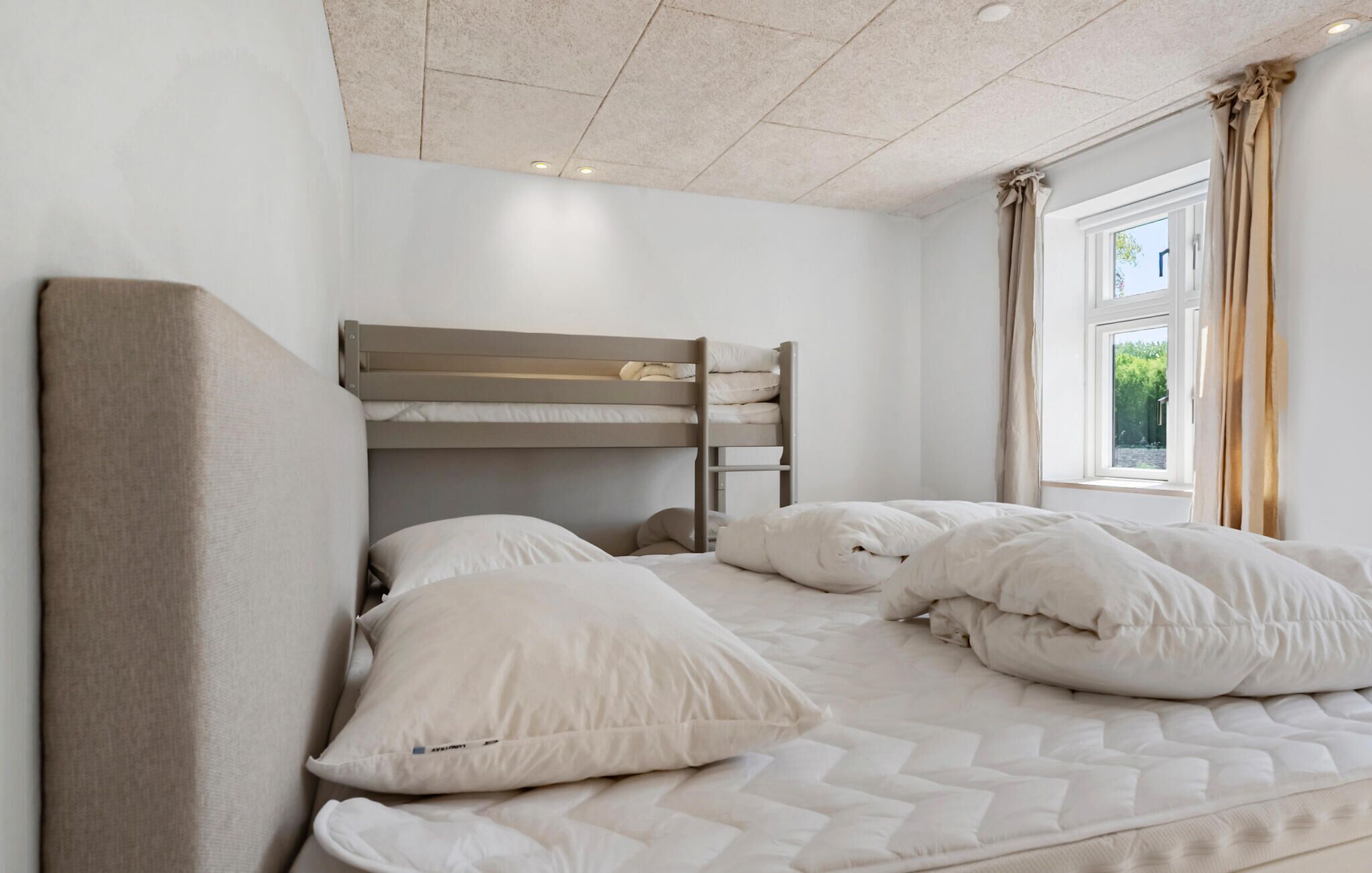 Una habitación con literas, una ventana con cortinas y vistas al exterior.