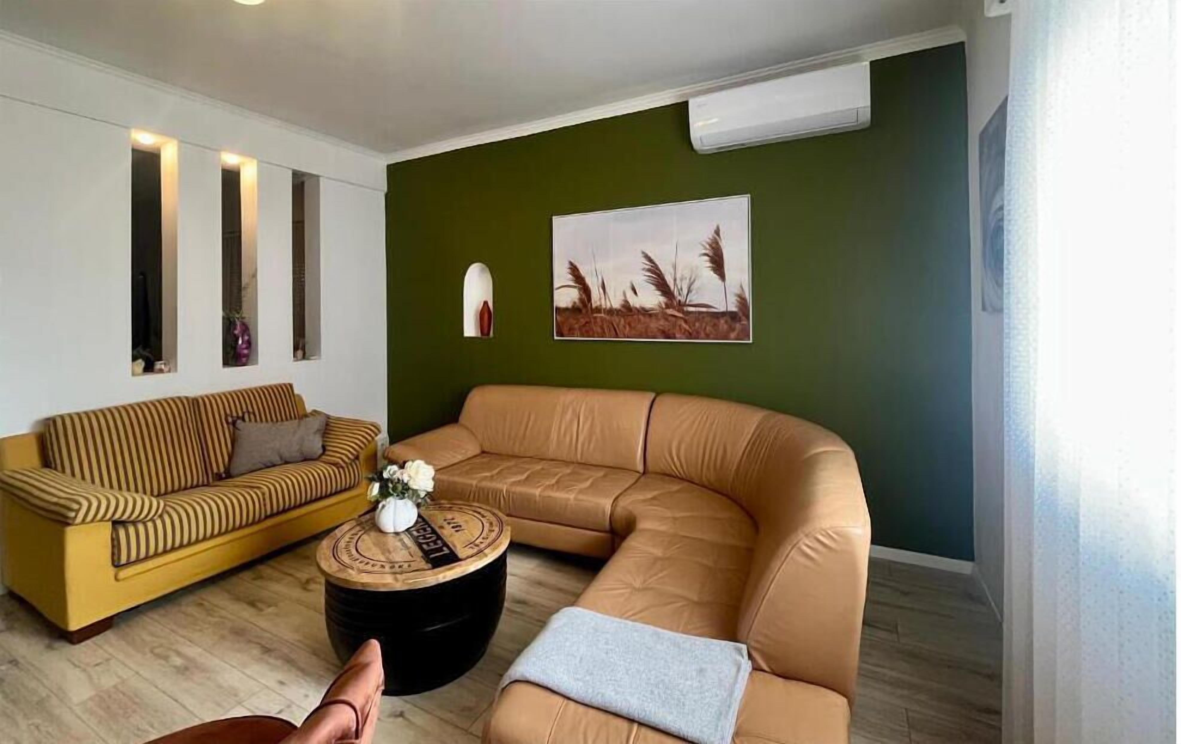 A living room with a striped sofa, a leather sectional, a round coffee table, and a painting on the wall.