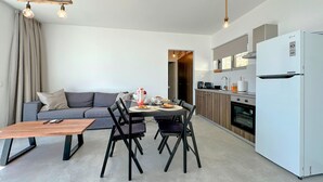 A modern kitchen with a white refrigerator, wooden cabinets, and a dining area with a table and chairs. - Amazing home in Xylokastro with house a mountain view (Xylokastro)
