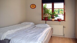 Un dormitorio con dos camas individuales, una ventana con plantas en macetas y un radiador.