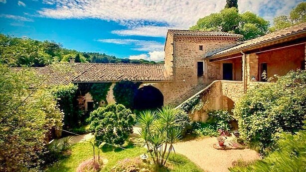 A courtyard with a stone building, a covered walkway, and lush greenery. - Stunning home in Sabran with heated swimming pool (Sabran)