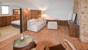 A cozy room with a wooden floor, a sofa, a small table with a teapot, and a stone wall. - Stunning home in Sabran with heated swimming pool (Sabran)