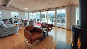 A spacious living area with a fireplace, large windows, and a view of the outdoors. - 4 bedroom nice home in Båstad (Båstad)