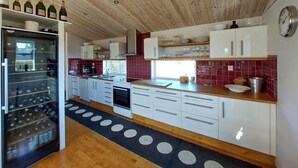 A modern kitchen with white cabinets, a wooden countertop, and a wine fridge. - 4 bedroom nice home in Båstad (Båstad)