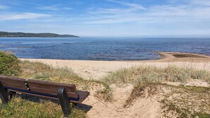A bench overlooking a beach with a clear view of the sea and distant hills. - 4 bedroom nice home in Båstad (Båstad)