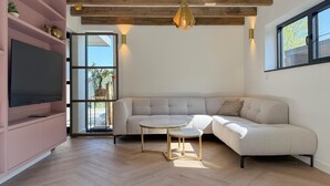 A modern living room with a sectional sofa, a flat-screen TV, and a small round table.