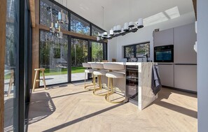 A modern kitchen with a bar area, large windows, and a view of the outdoors. - Cozy home in Ouddorp with WiFi (Ouddorp)
