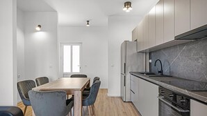 A modern kitchen with a marble countertop, stainless steel appliances, and a dining area with a wooden table and chairs. - Stunning apartment in Pirovac with WiFi (Pirovac)