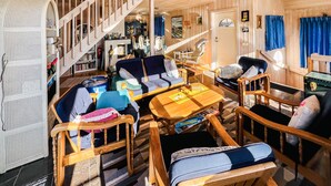 A cozy cabin interior with a wooden staircase, a dining table with chairs, and a variety of seating options. - 5 bedroom lovely home in Tanumshede (Tanumshede)