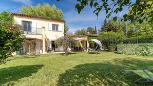 Une maison à deux étages dotée d’un patio, d’un espace extérieur aménagé avec des sièges et d’une pelouse bien entretenue.